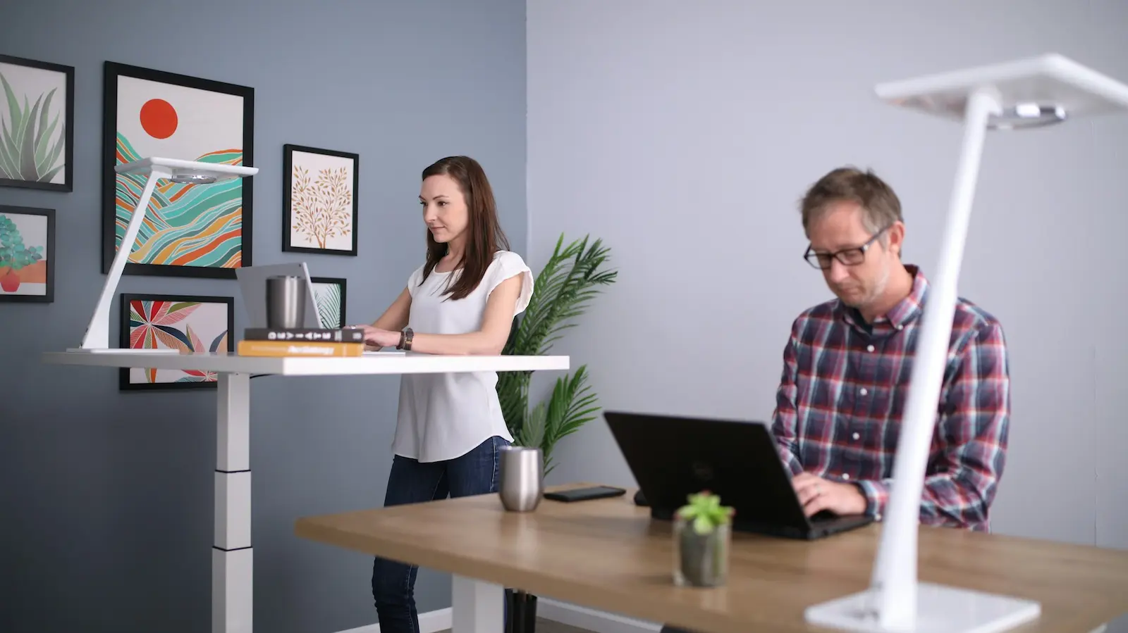 Person wechselt zwischen Stehen und Sitzen am höhenverstellbaren Schreibtisch im Homeoffice