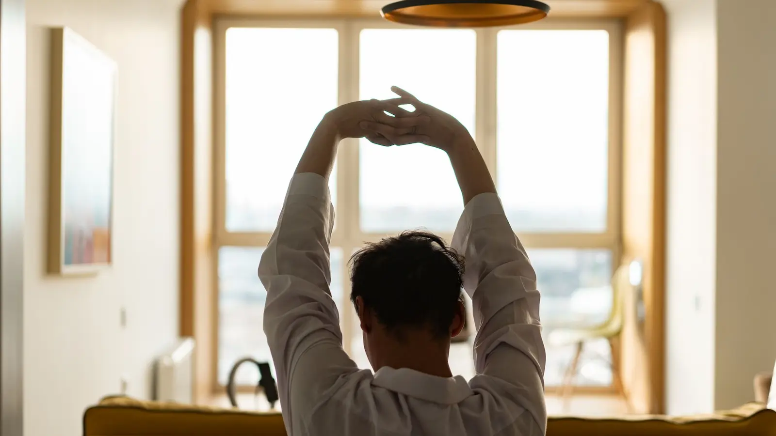 Frau macht Dehnübungen am Schreibtisch im Homeoffice – Nacken-Stretching gegen Verspannungen