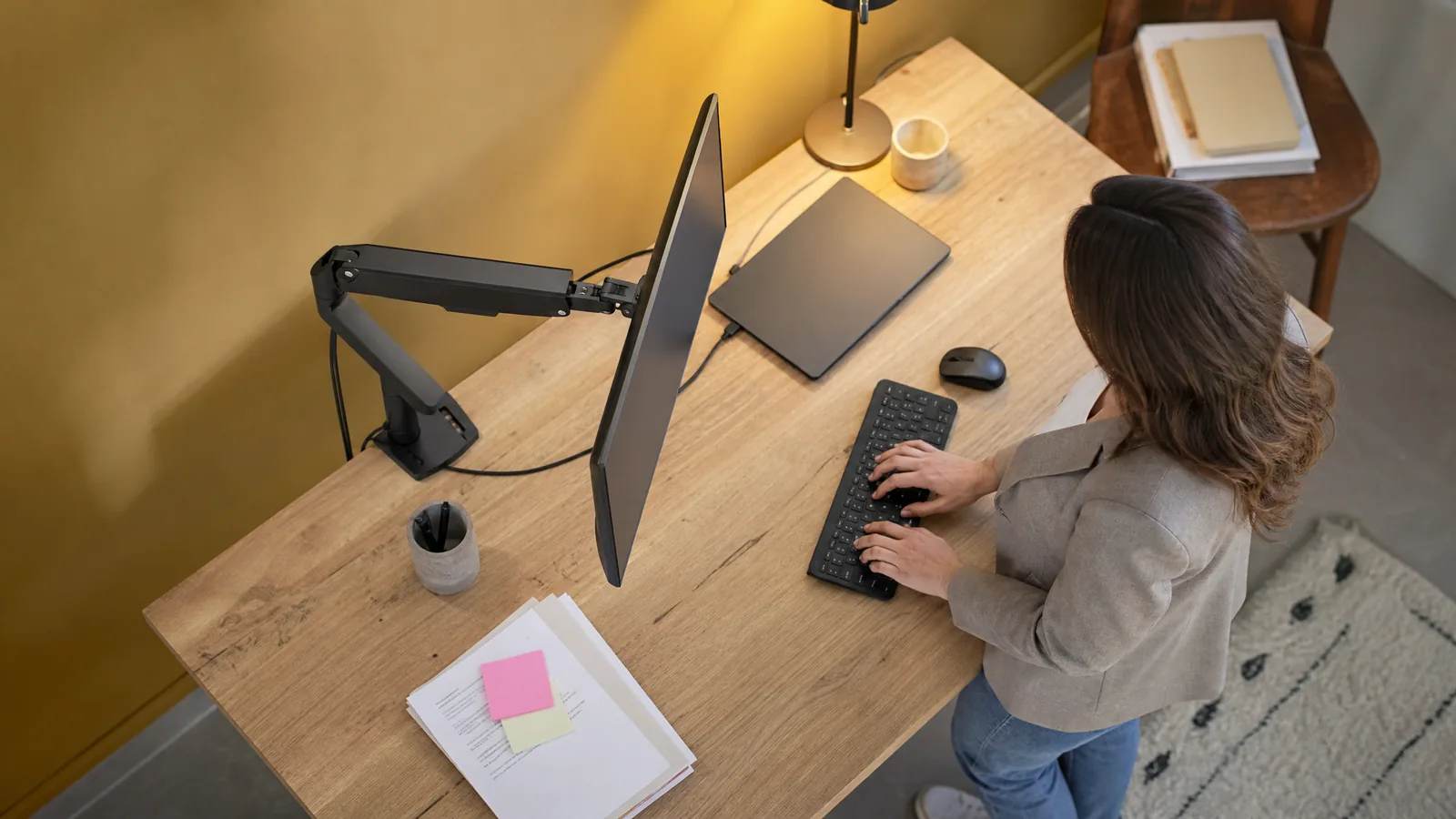 Monitorarm mit Gasfeder hält einen Bildschirm über einem Holzschreibtisch – Symbolbild für den Monitorarm-Vergleich